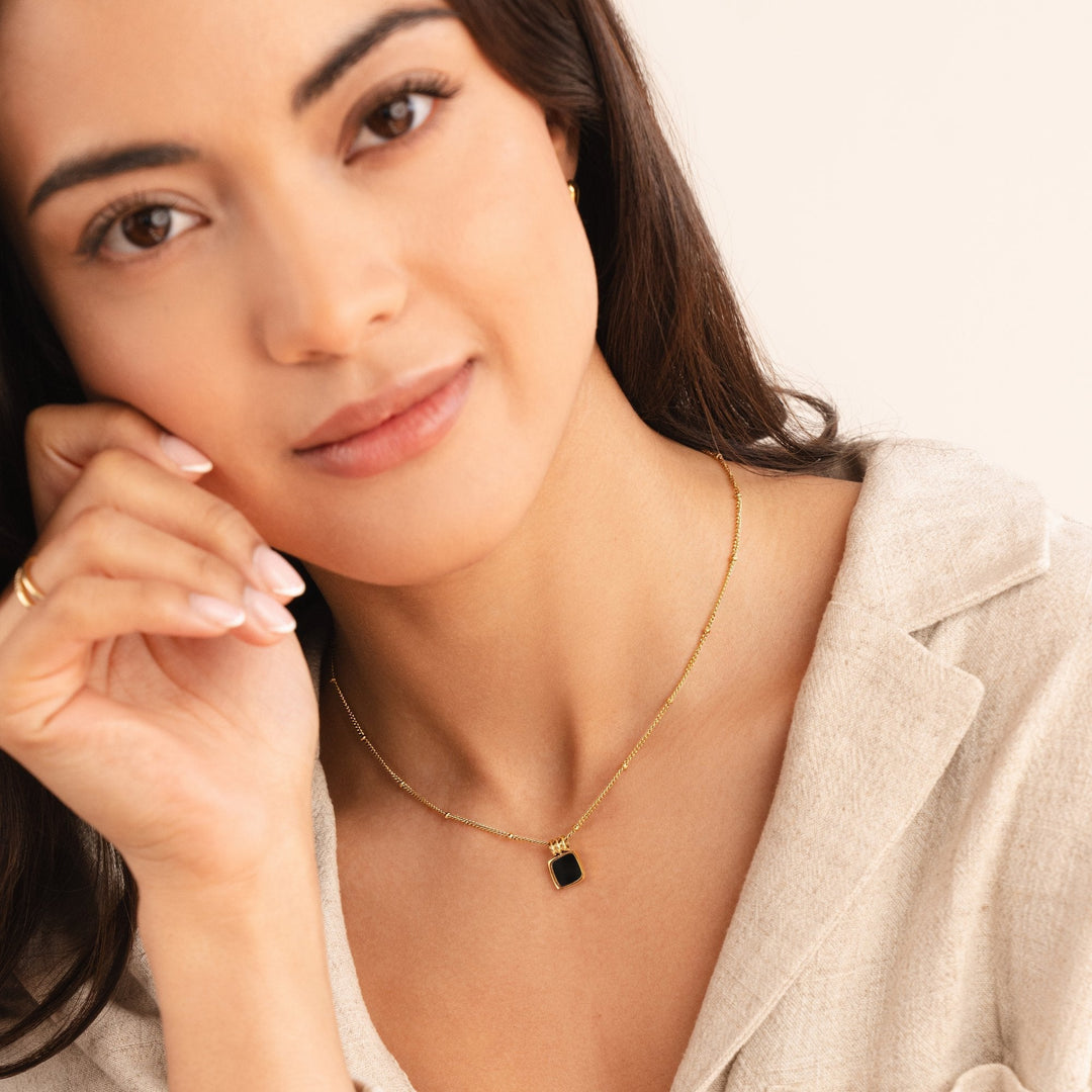 Selina – Goldene Halskette mit dunklem Stein.